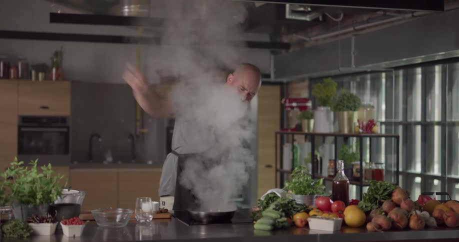 A chef pours alcohol into a pan and sets it on fire