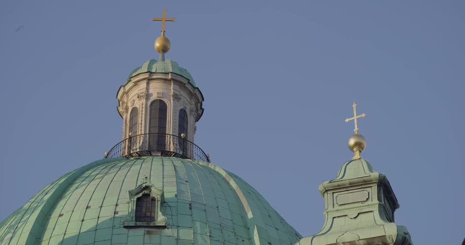 A cross adorns the bell tower of a domed building