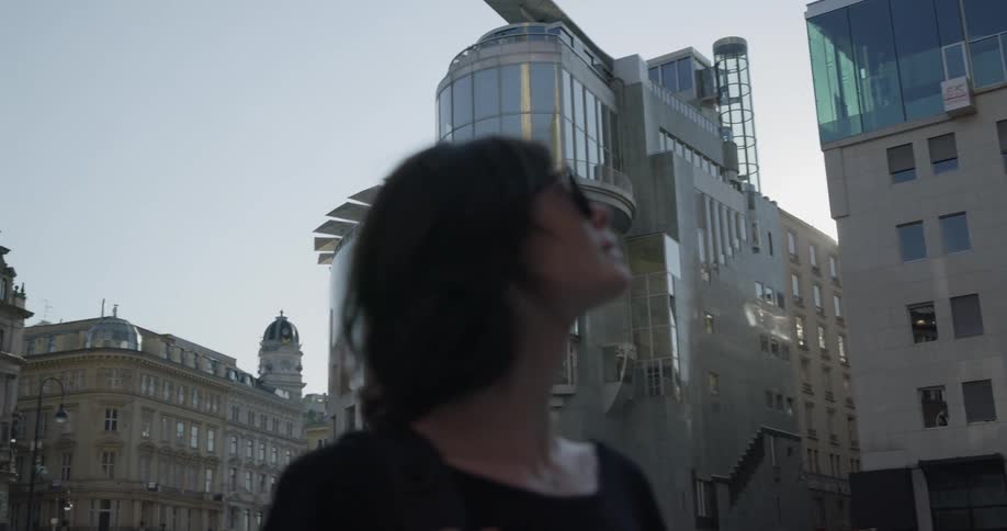 A woman looks up at the buildings around her