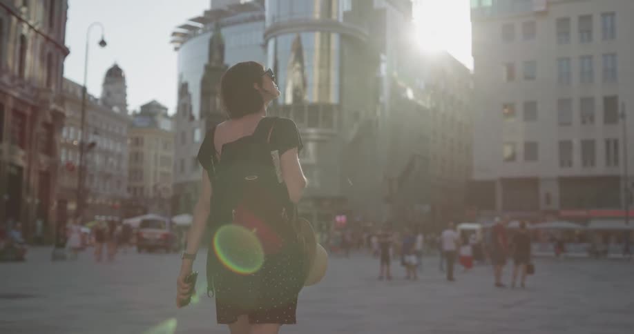 Woman wearing sunglasses walks down city square during daylight in the city