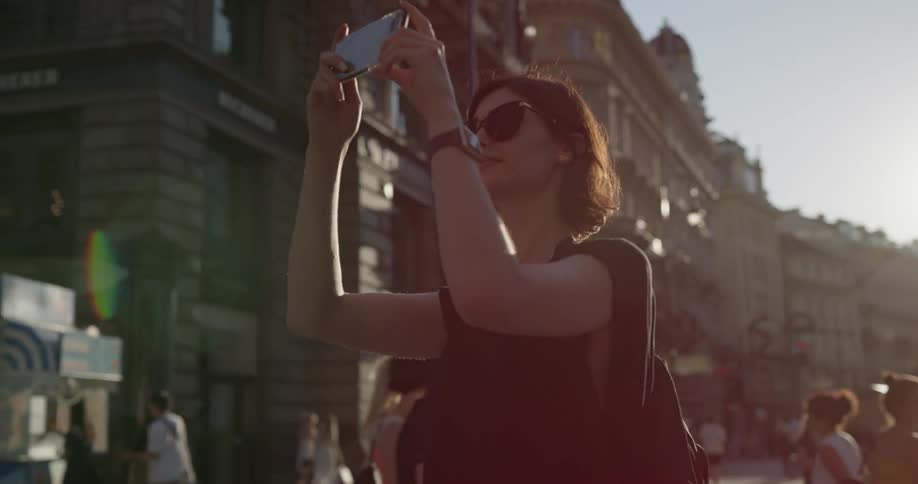 Female tourist taking a selfie on her phone in the downtown area