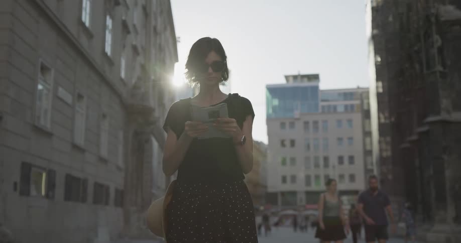 A woman looks at a paper and to the city buildings that surround her