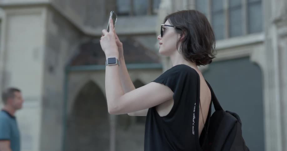 A woman walks outside and takes a photograph