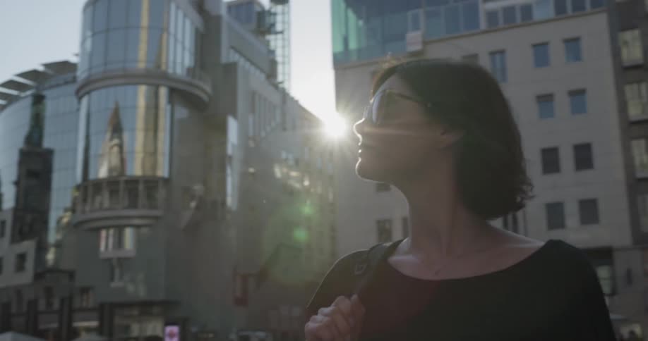 Woman stands looking around city block