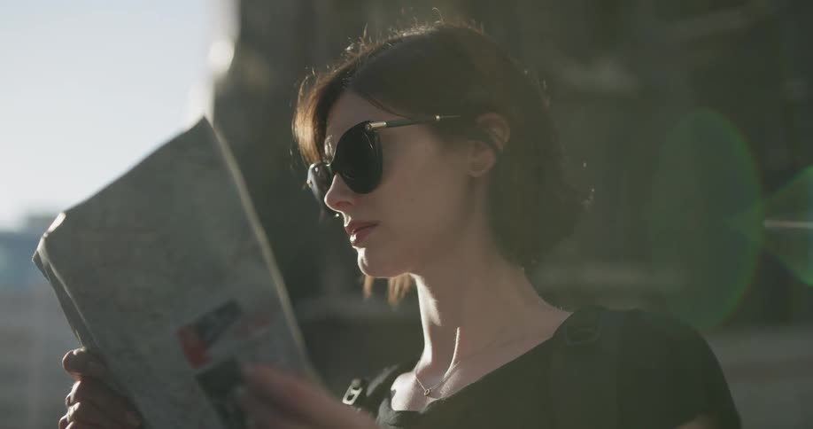 A woman outside in the daytime reading a map
