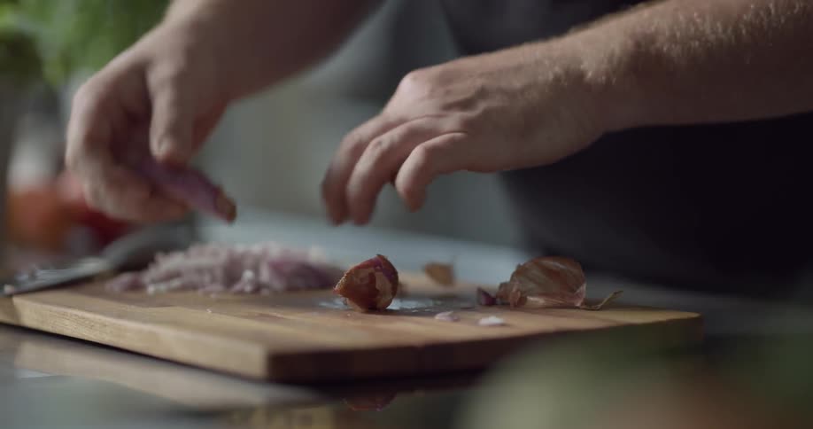 A man carefully slices a piece of vegetable in half before peeling away at its outer layers