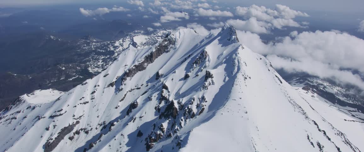 A mountain peak sits higher than a layer of clouds