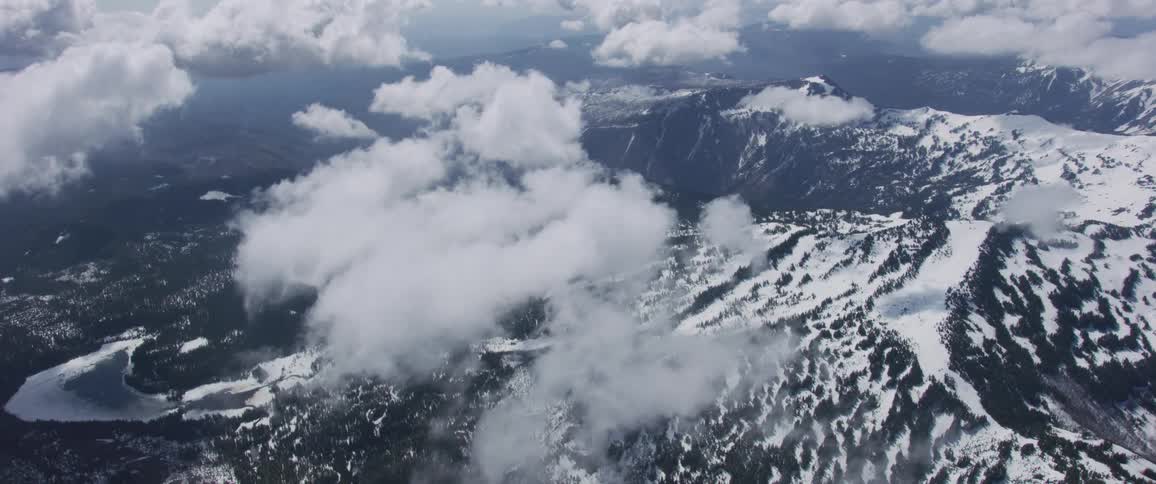 Clouds hang over snow covered mountain ridges and slopes