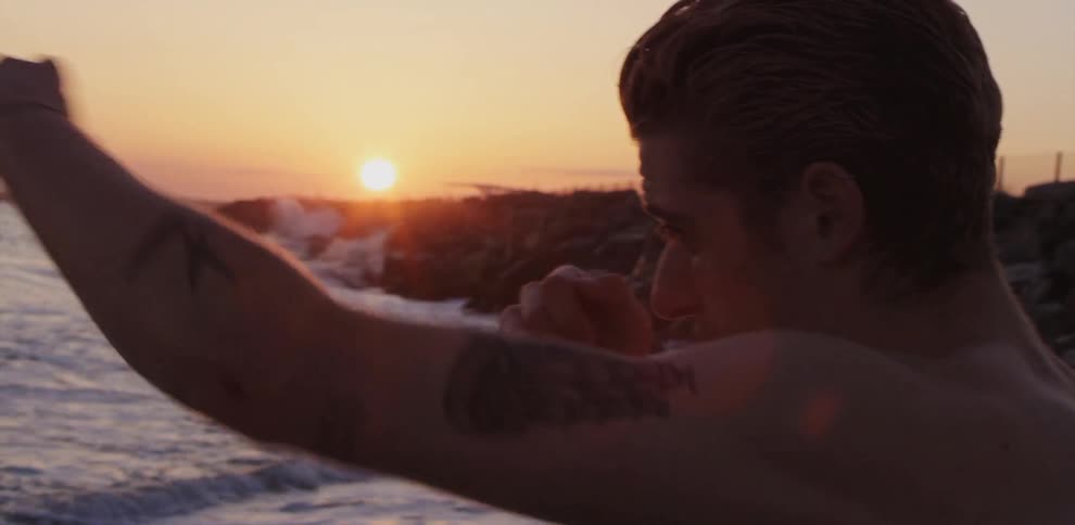 A man throwing punches while standing at the edge of the ocean