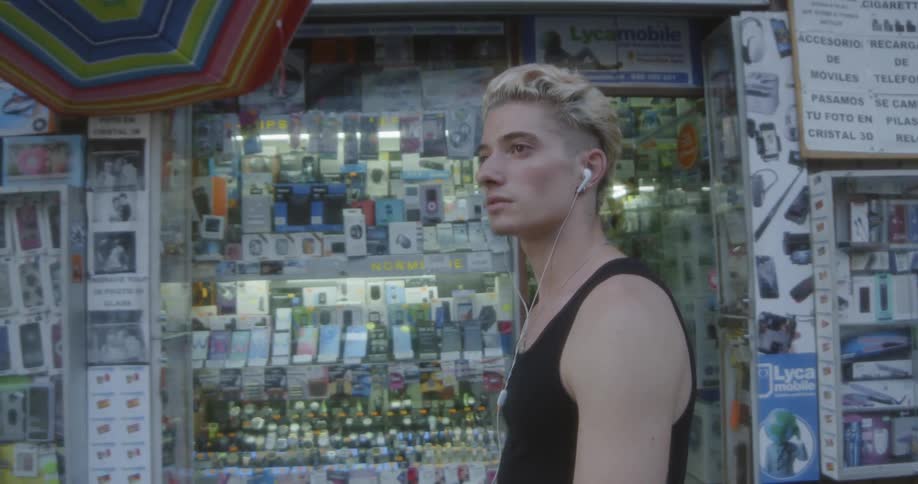 A teenager walks along the street with earbuds in