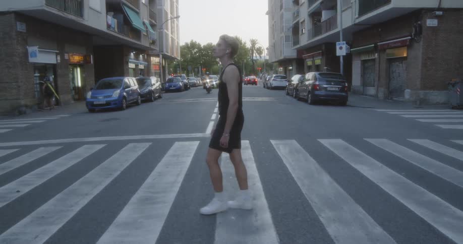 A white man walks across a crosswalk in a city