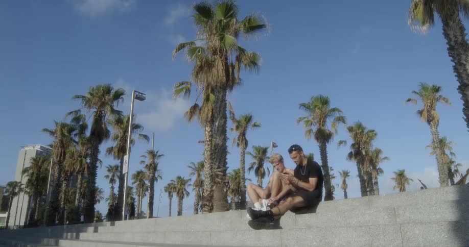 Two men sitting on steps looking at a phone