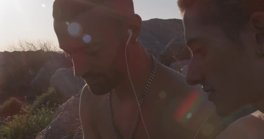 Two teenagers sit together each with an earbud in