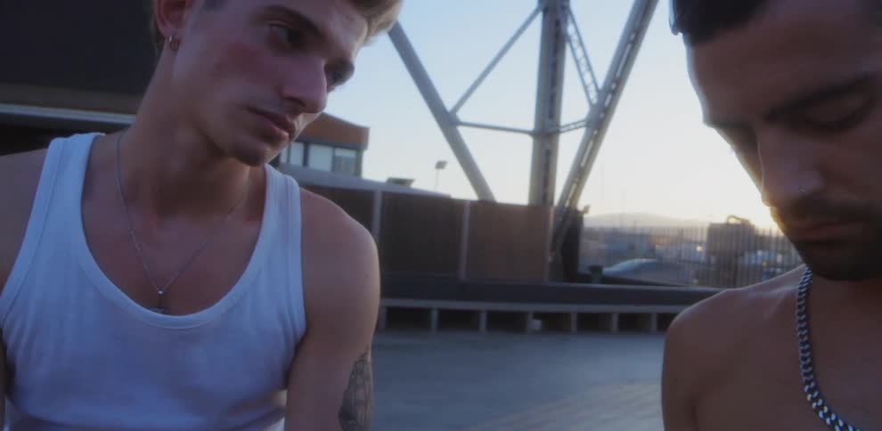 A teenager looks down at something while the other looks at him