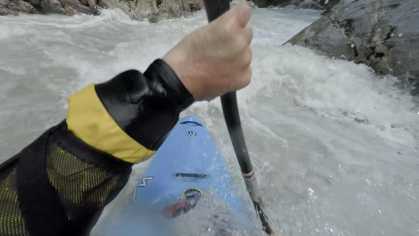 A person is skillfully paddling their kayak through the highly turbulent rapids of a racing river