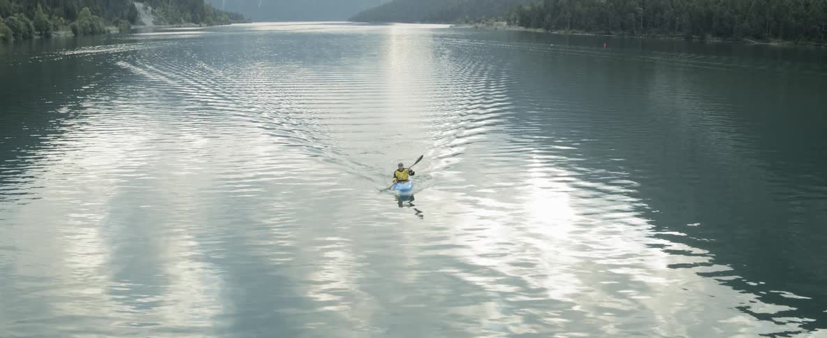 A person kayaking in calm waters reflecting the sun