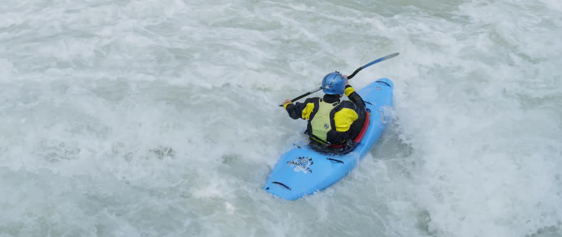 A person kayaks down whitewater rapids