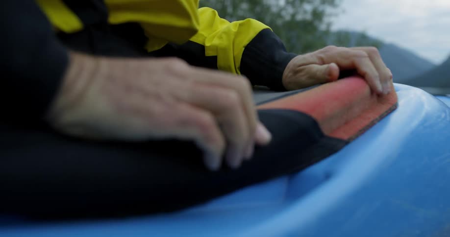 A man stretches a cloth over a kayak