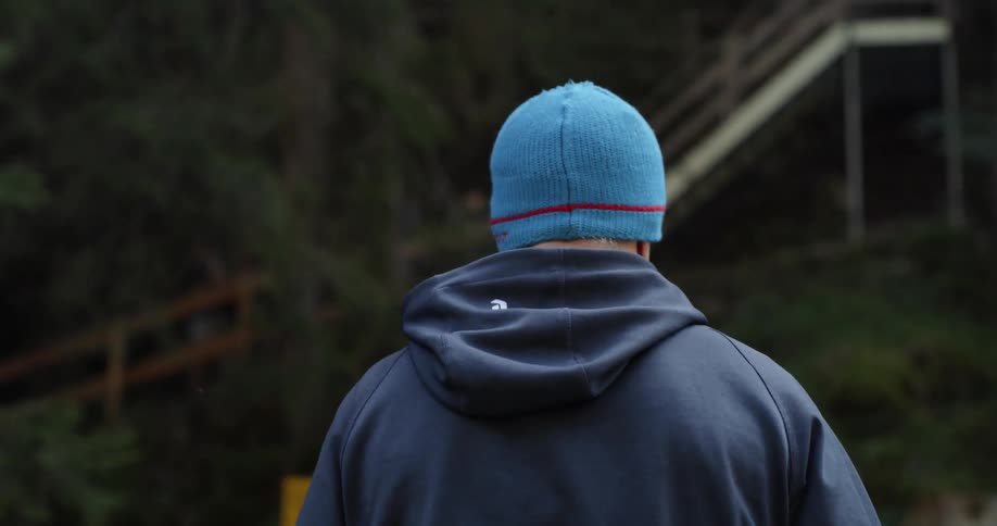 A man with a blue hat and a hoodie walking outside