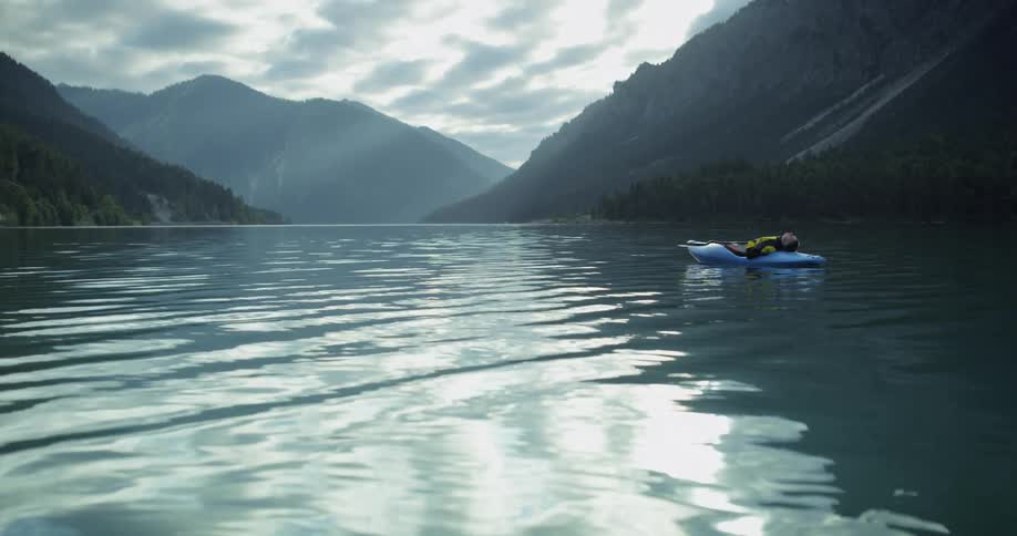 A person laying on a raft on a calm river
