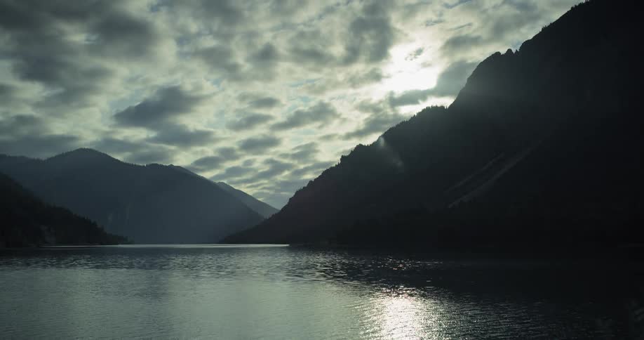 Clouds move overhead as water ripples next to mountains