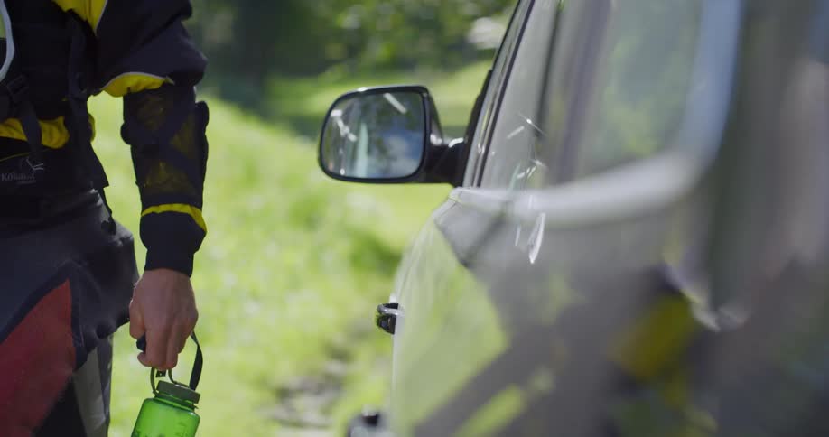 A man is walking to his car while holding a water bottle