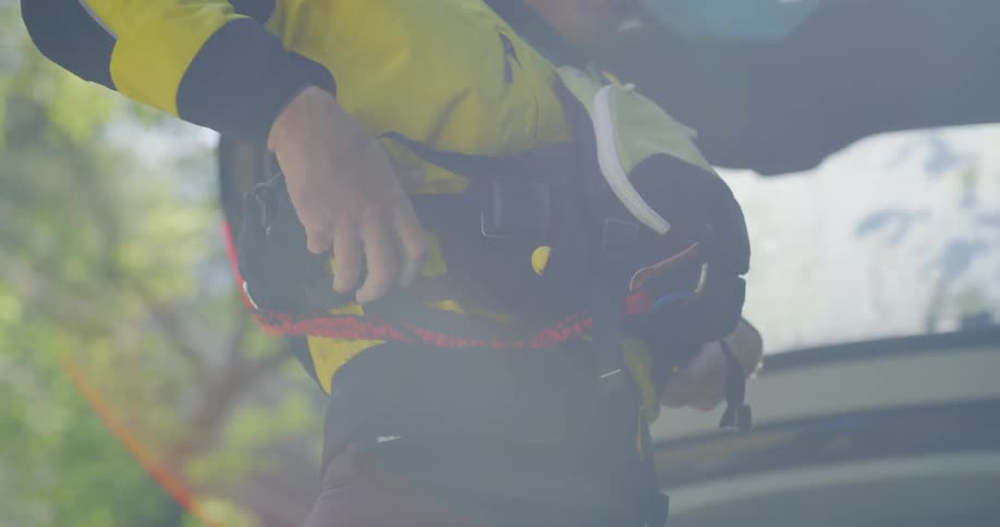 A white man adjusts the belts on his vest
