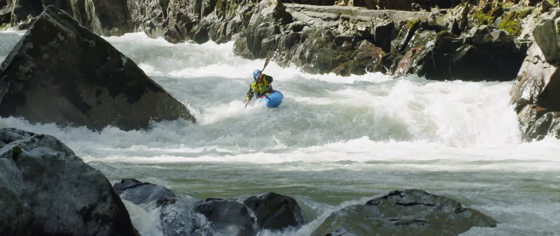 A kayaker goes over rapids on a river