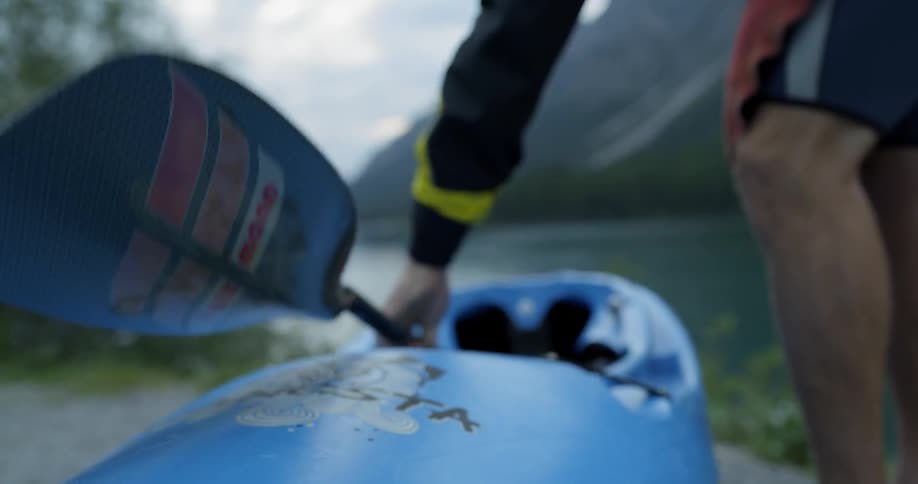 Male putting paddle inside a canoe near a lake