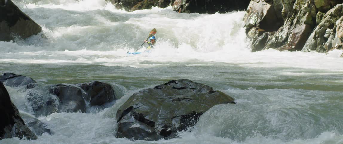 A man kayaks down the white water rapids of a river