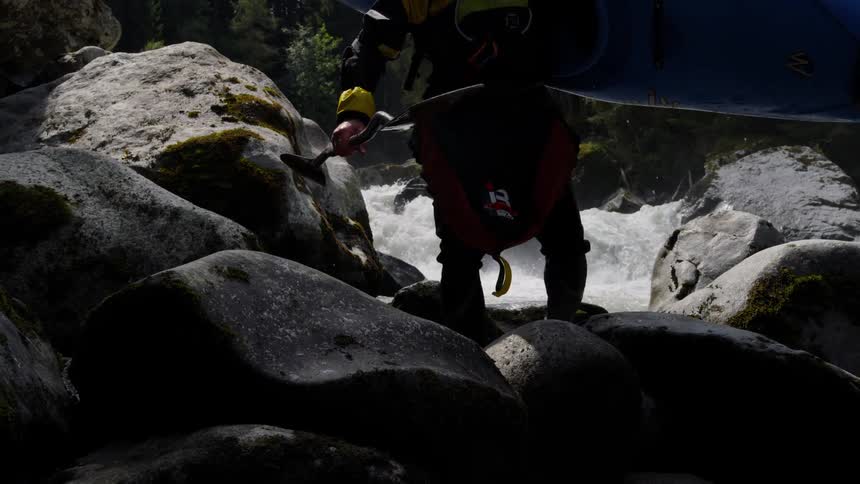 A man is carrying a kayak along the river
