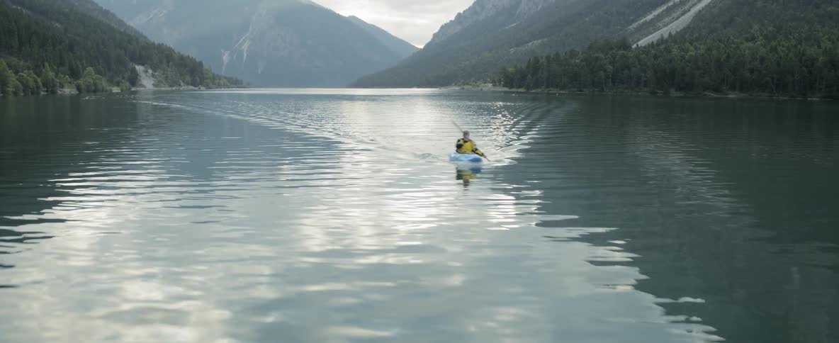 A man in a kayak rows across a lake