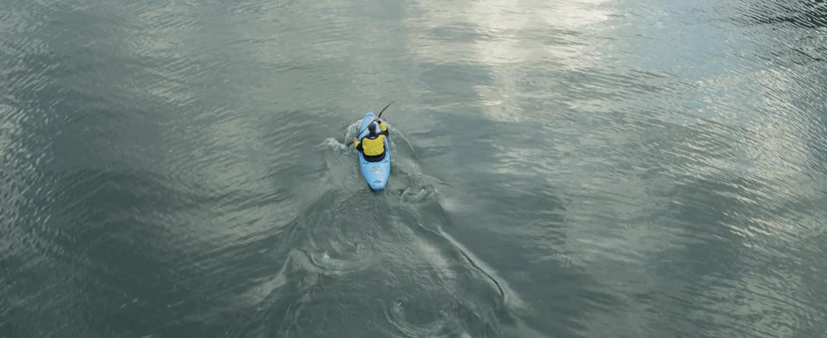 A kayaker paddles across a body of still water