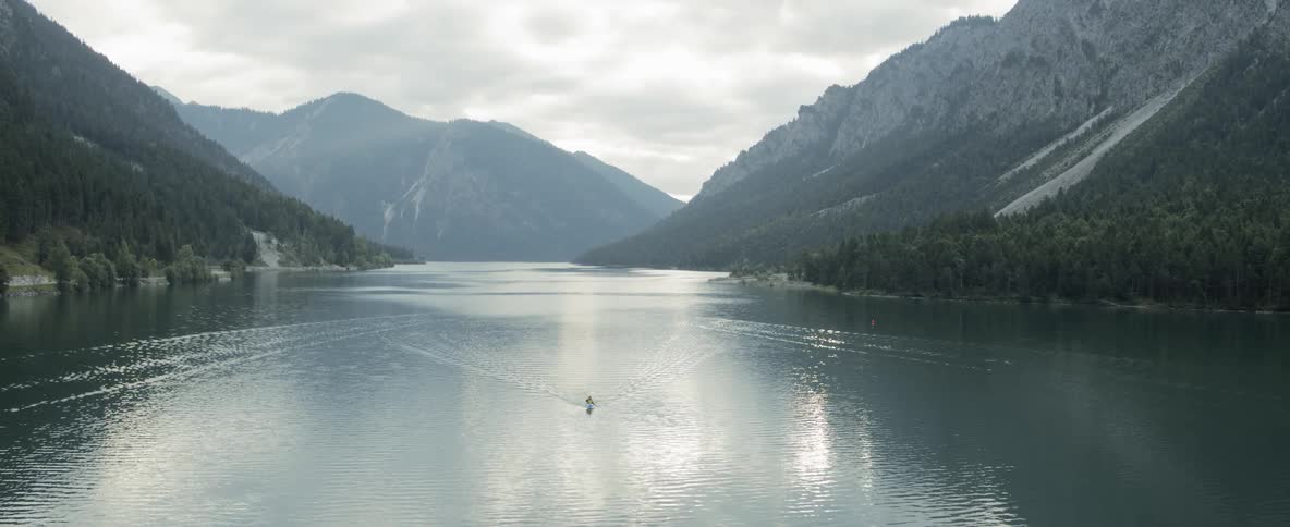 The lone man in the kayak is going so fast he is creating a wake in the water