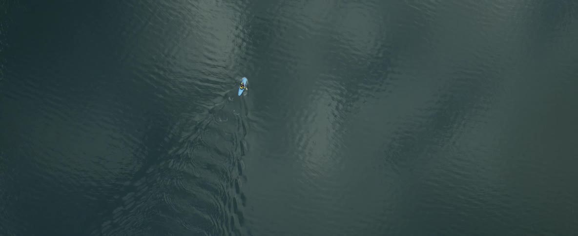 A kayaker paddles across a body of still water