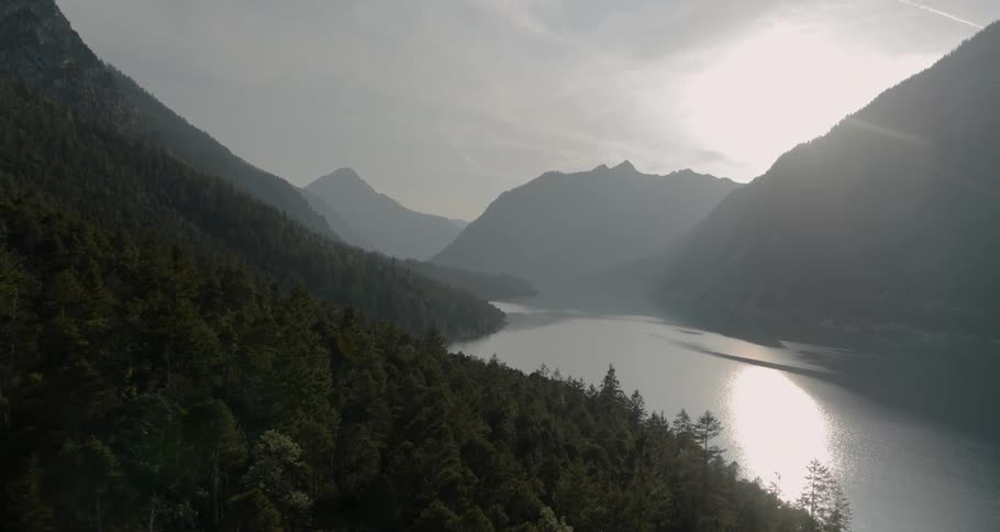 Waterway fills valley between forest covered mountains