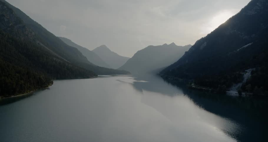 The camera flies over a lake nestled between mountains