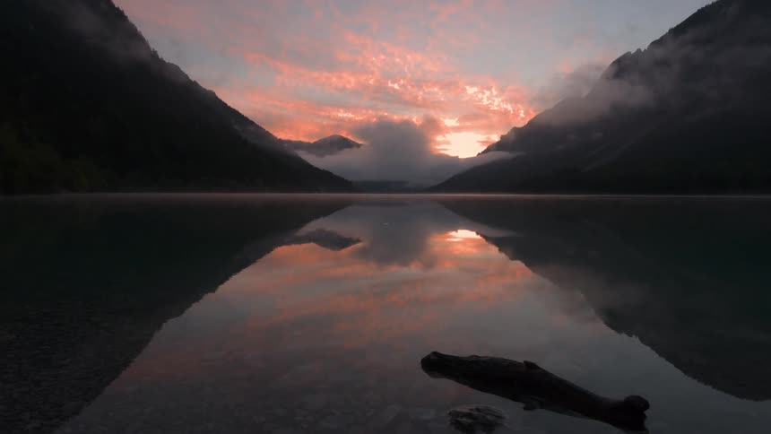 Sunset reflected on lake between mountains