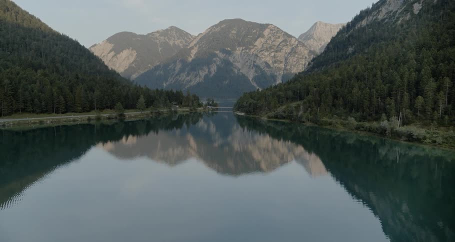 A reservoir is surrounded by forest and mountains