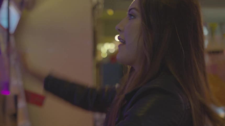 A young female throws a ball and smiles in a room of flashing lights