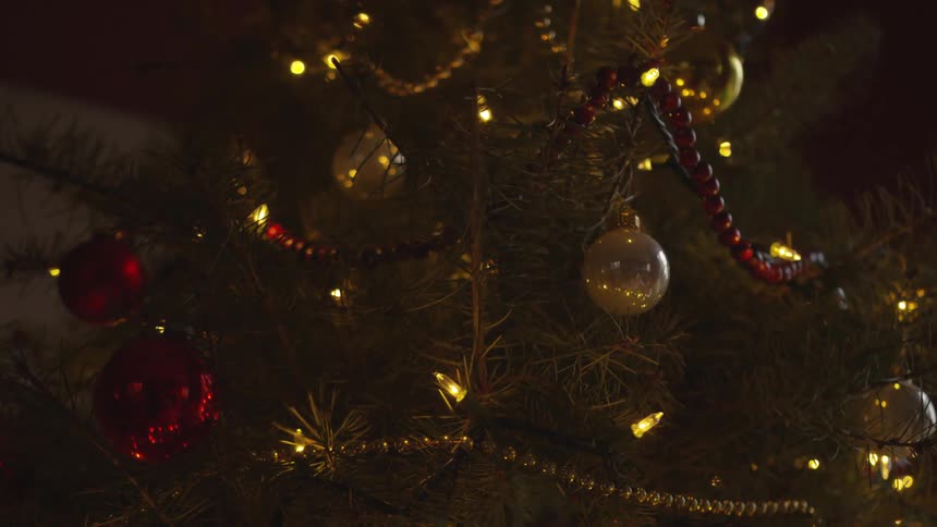 A christmas tree decorated with red and white baubles at night