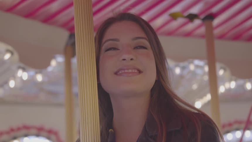 A woman flips her hair and smiles at the camera