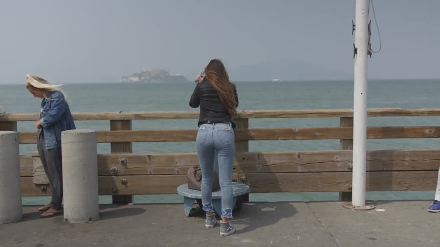 A woman is looking through a telescope outside at an island
