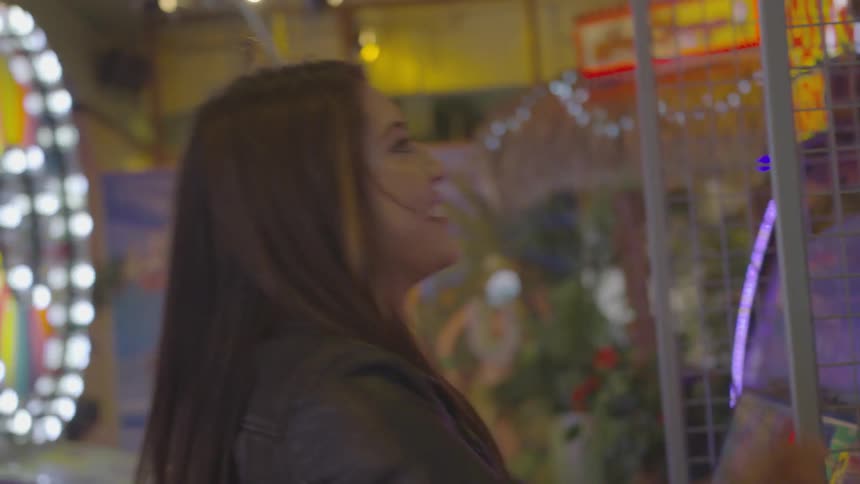 A woman smiles as she shoots a basketball playing an arcade hoop game