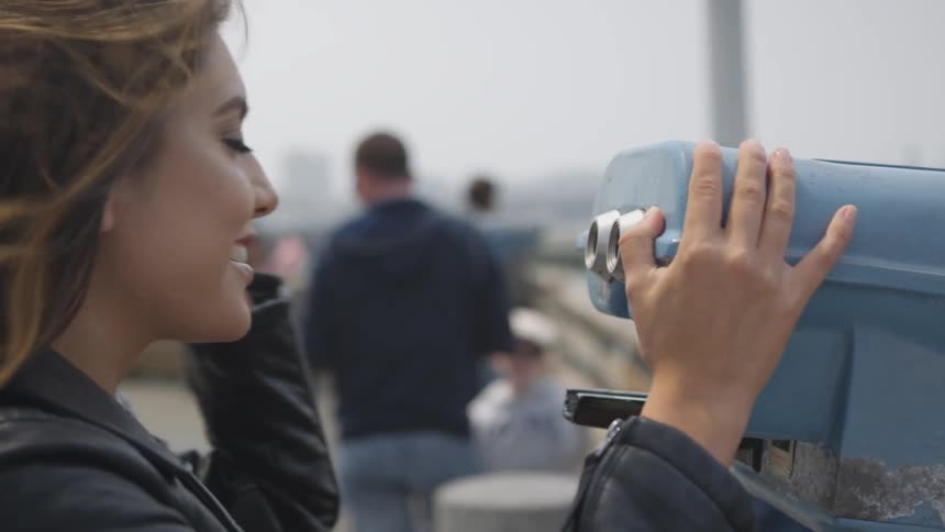 Woman looks through a coin operated binocular