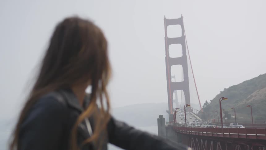 A young woman looking out over a traffic bridge on a foggy day