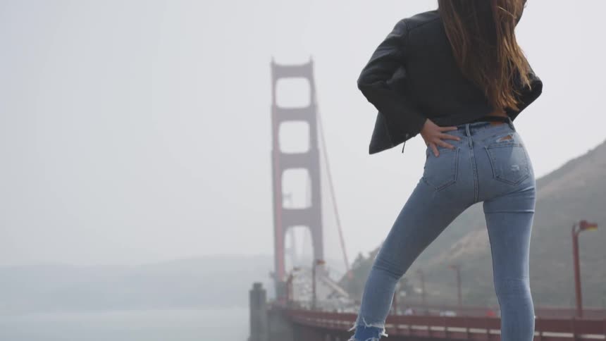 A woman posing in front of a bridge