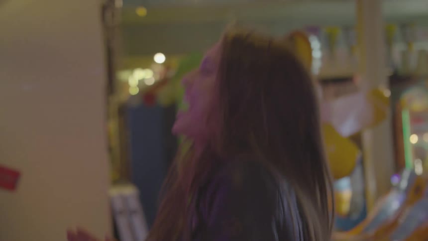 A young woman doing a celebration dance in an arcade