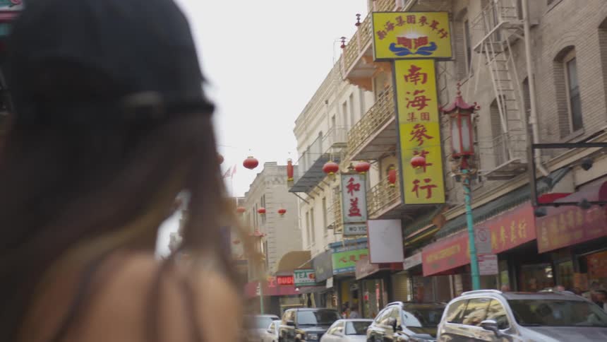 A dark haired female is looking around in a downtown area