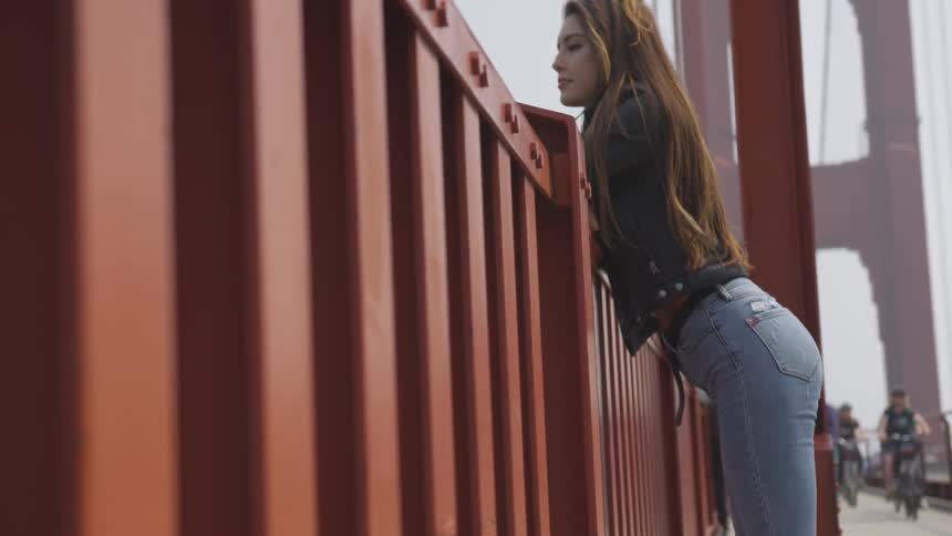 A woman leaning over a bridge guardrail